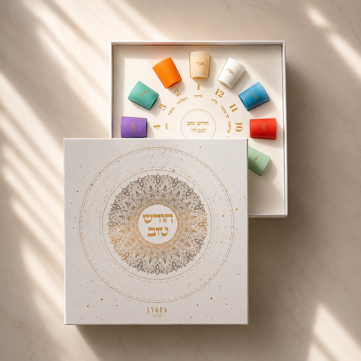 Coffret Rosh Hodesh Lyora : douze bougies colorées disposées en cercle façon calendrier et l'écrin blanc au mandala doré « Hodesh Tov »